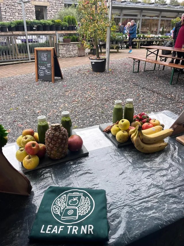 Leaf TRNR green smoothies displayed with fresh fruit at an outdoor market.